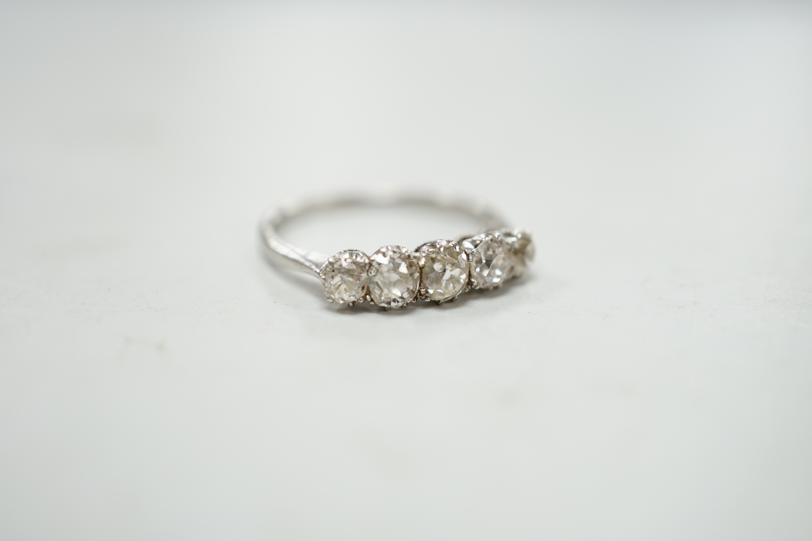 A 1940's white metal and graduated five stone diamond set half hoop ring, size M/N, gross weight 2.8 grams.